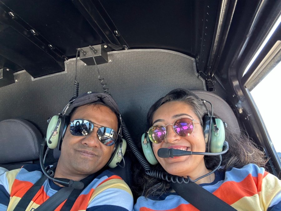 Praddy and Meenu in headsets, smiling, in the helicopter