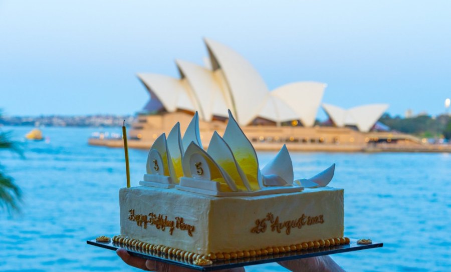 Meenu's birthday cake, topped with white sails like a miniature Opera House, in front of the real one