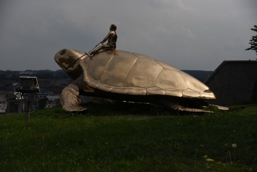 A giant golden turtle with a rider on its back, on the grass at Namur's citadel