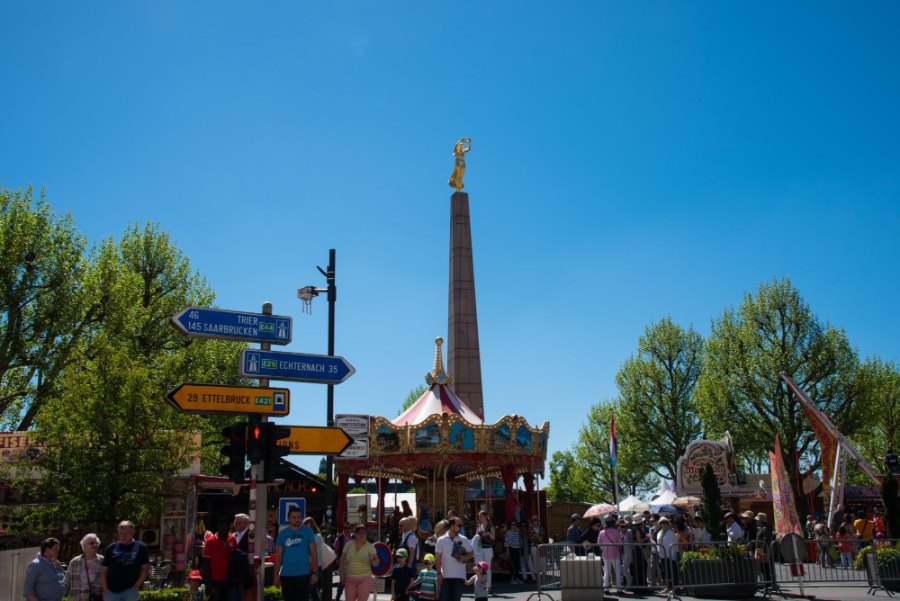 The Gëlle Fra, a golden figure on a tall obelisk, above a fair with a carousel