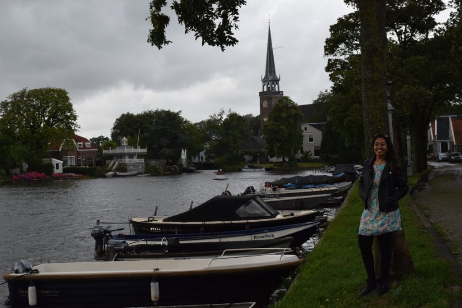 Small boats moored along the lake at Broek in Waterland under a tall church spire, with Meenu by a tree