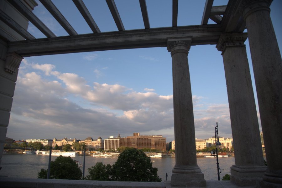 Stone columns of a pergola framing the Danube and the Pest riverfront in the evening sun