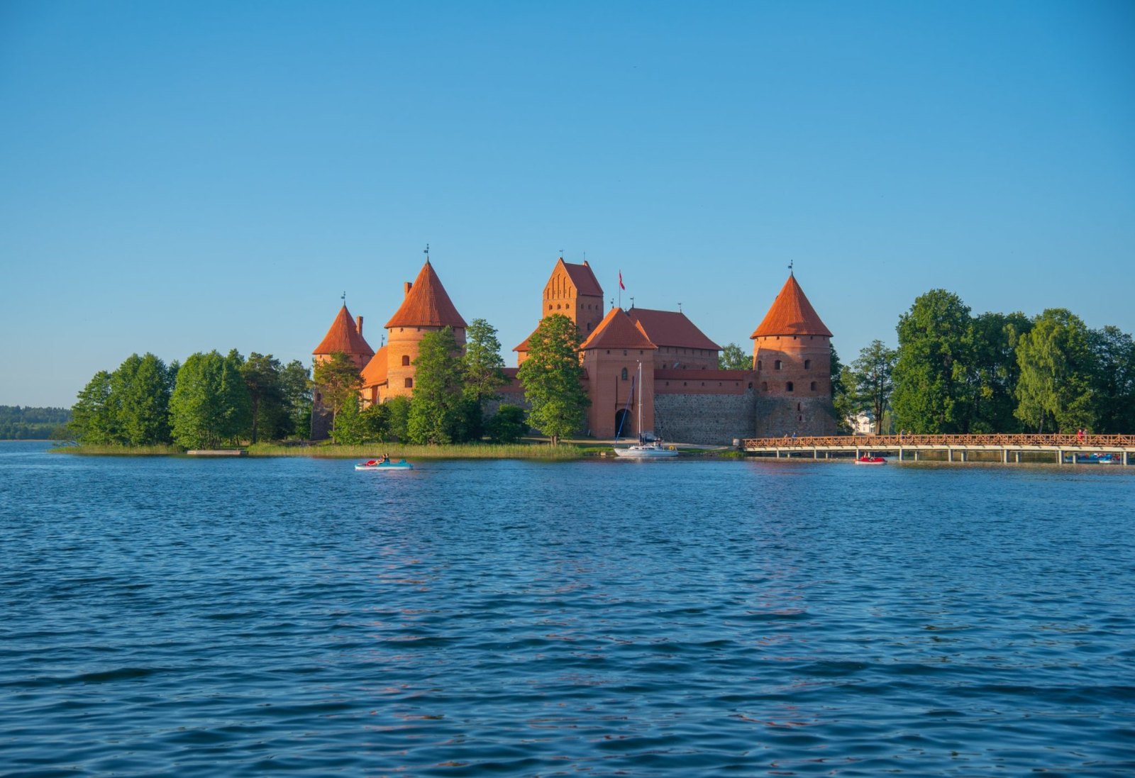 Trakai's red-brick island castle and its pointed towers across the blue water of the lake