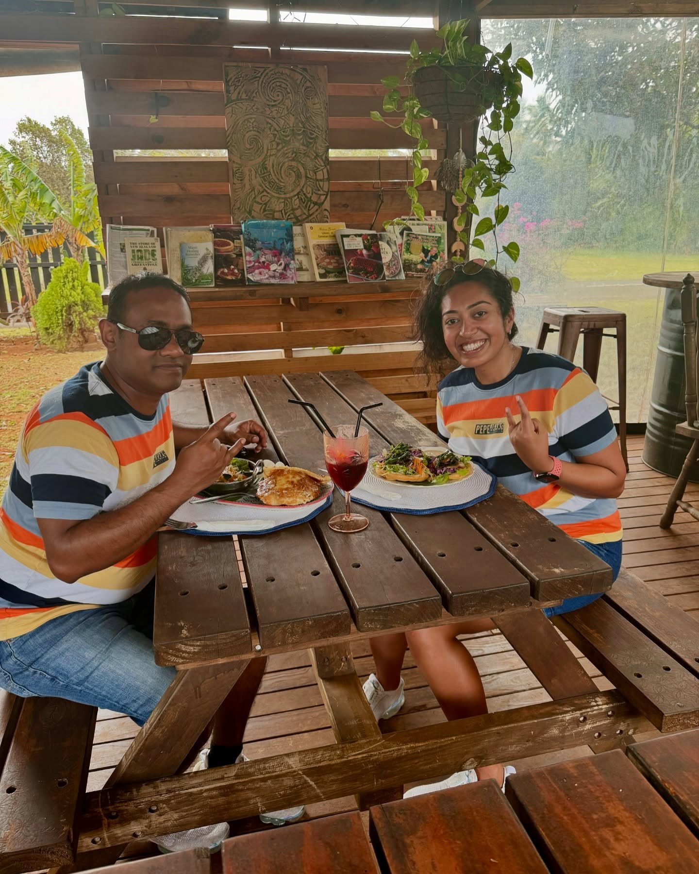 The two of us in matching striped T-shirts at a wooden table at Avatea Cafe, with our food and drinks