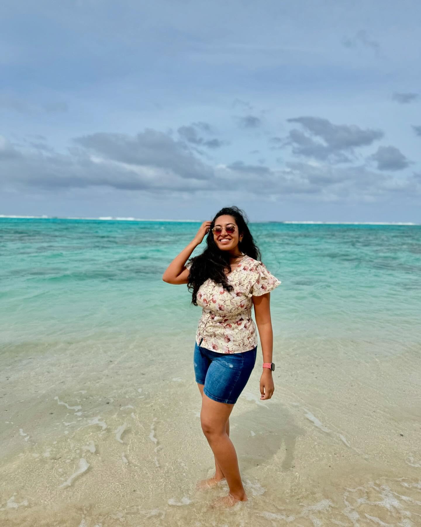 Meenu standing in the shallow lagoon at Little Polynesian, with waves breaking on the reef behind her