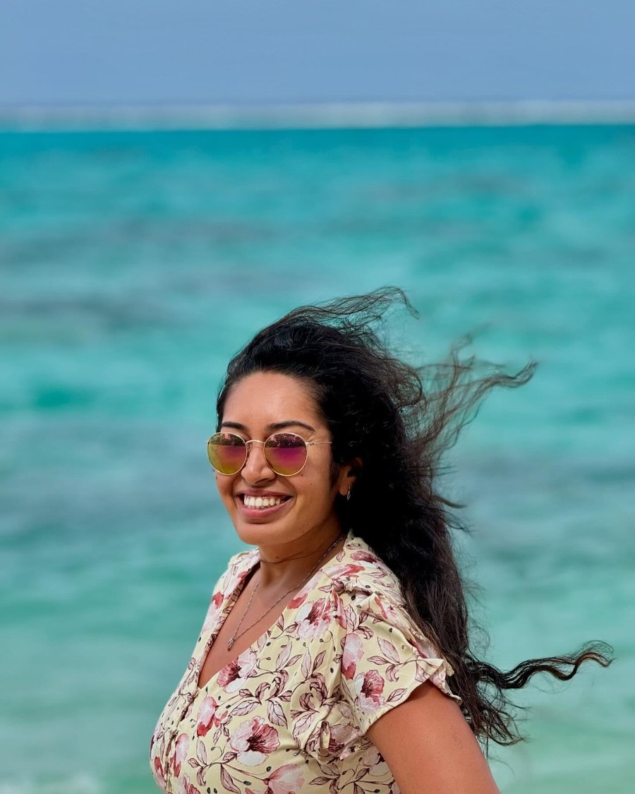 Meenu smiling as the wind catches her hair, with the turquoise lagoon behind her