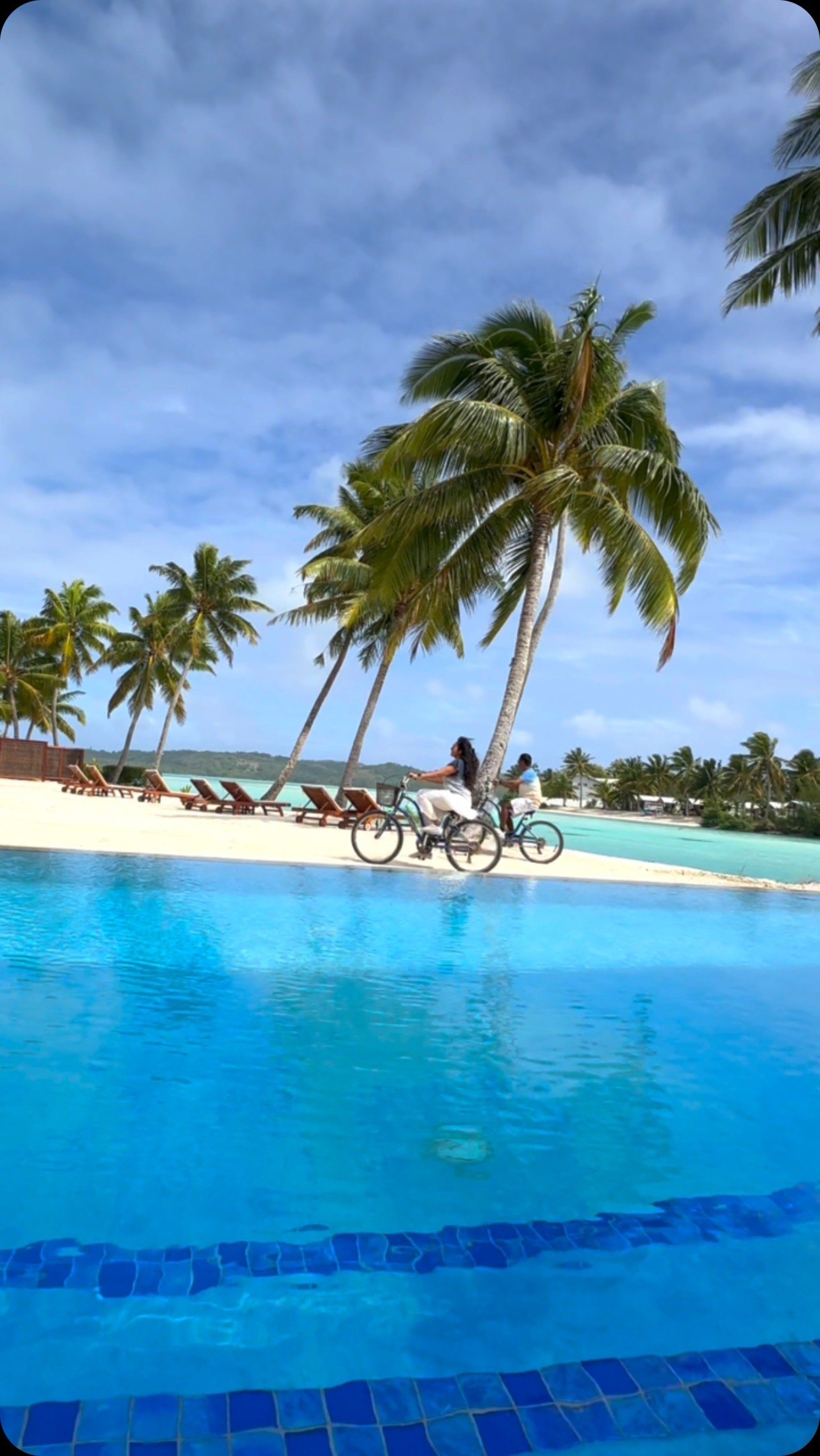 The pool at Aitutaki Lagoon Private Island Resort, with palms, loungers and the beach beyond