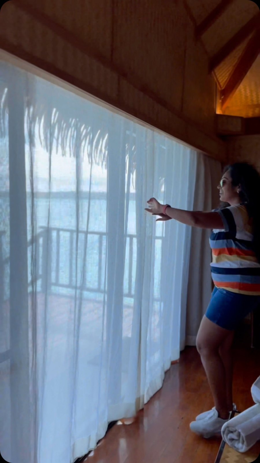 Meenu drawing back the curtains of our overwater villa to the lagoon