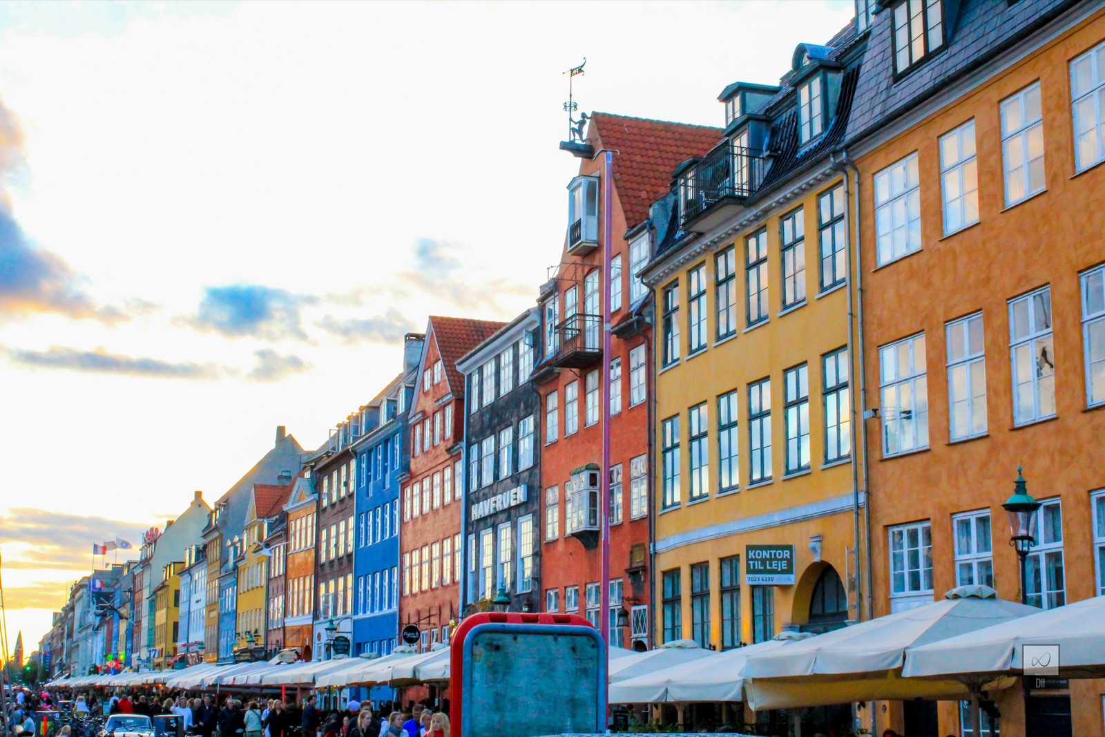 Nyhavn's tall painted houses in red, blue, yellow and orange, above crowded tables along the canal