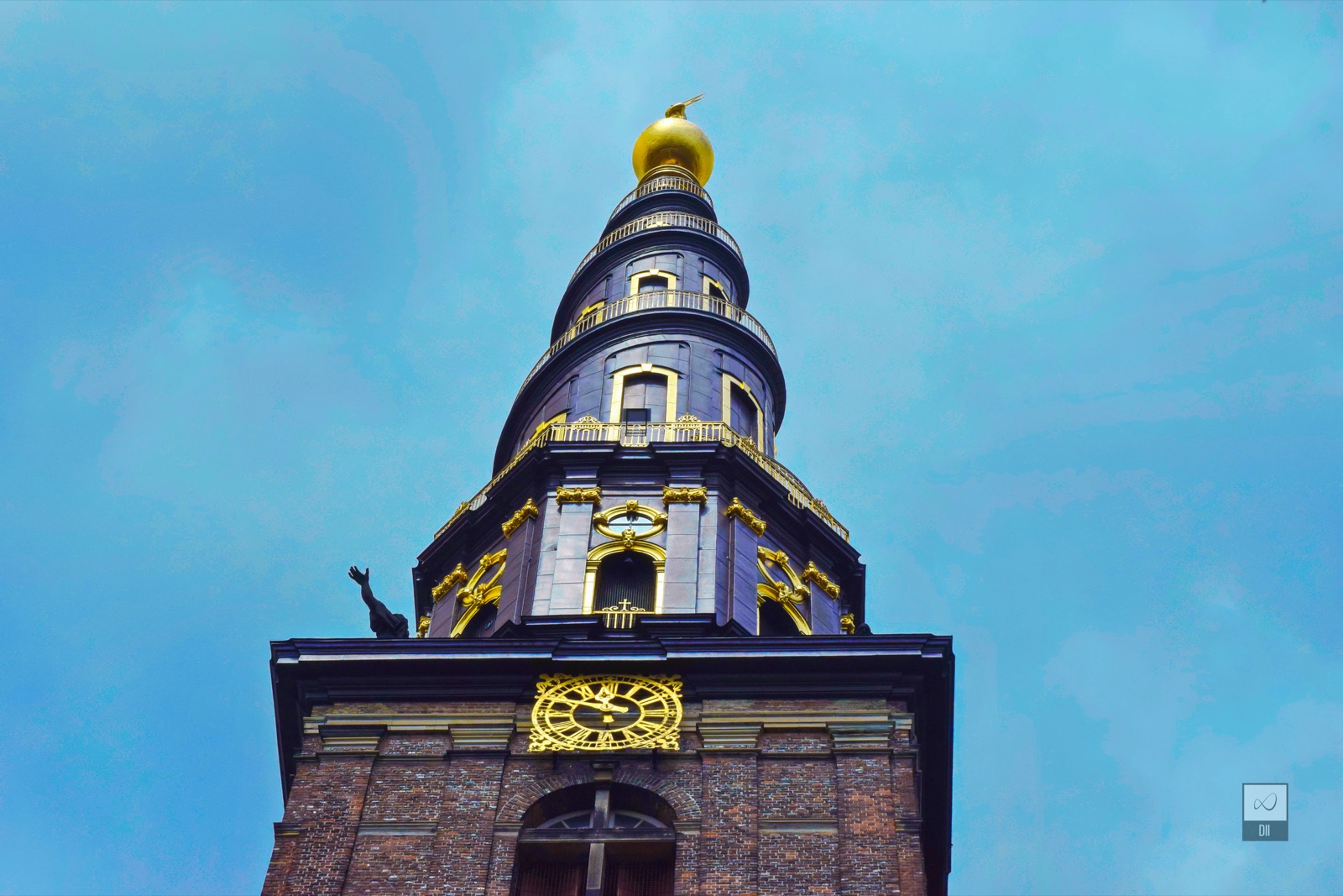 The dark spire of the Church of Our Saviour, trimmed in gold, against a blue sky