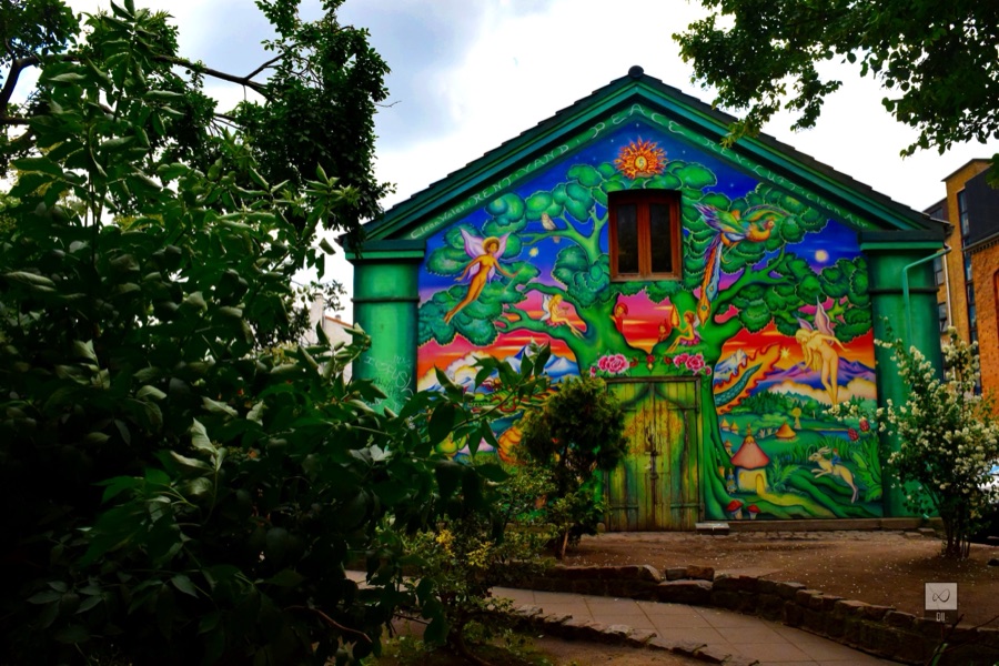 A house in Christiania covered in a bright mural of green trees and figures
