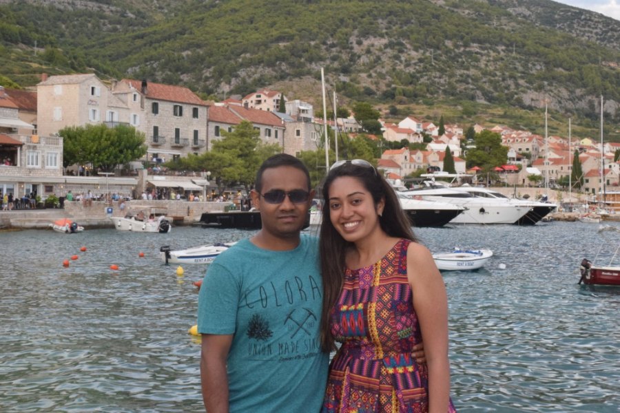 Meenu and Praddy smiling on the quay, with Bol's harbour and houses behind