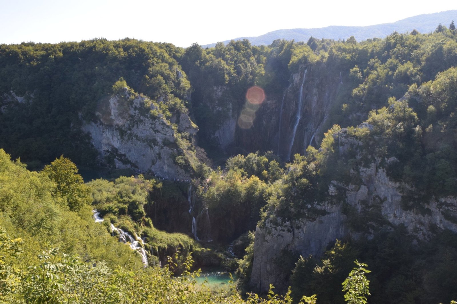 Looking down into the wooded canyon at the Plitvice Lakes, with a thin waterfall on its far wall