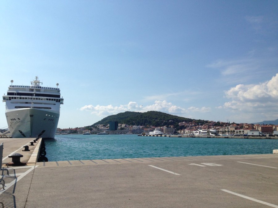 A cruise ship at the long pier in Split's harbour, with the town and Marjan across the water