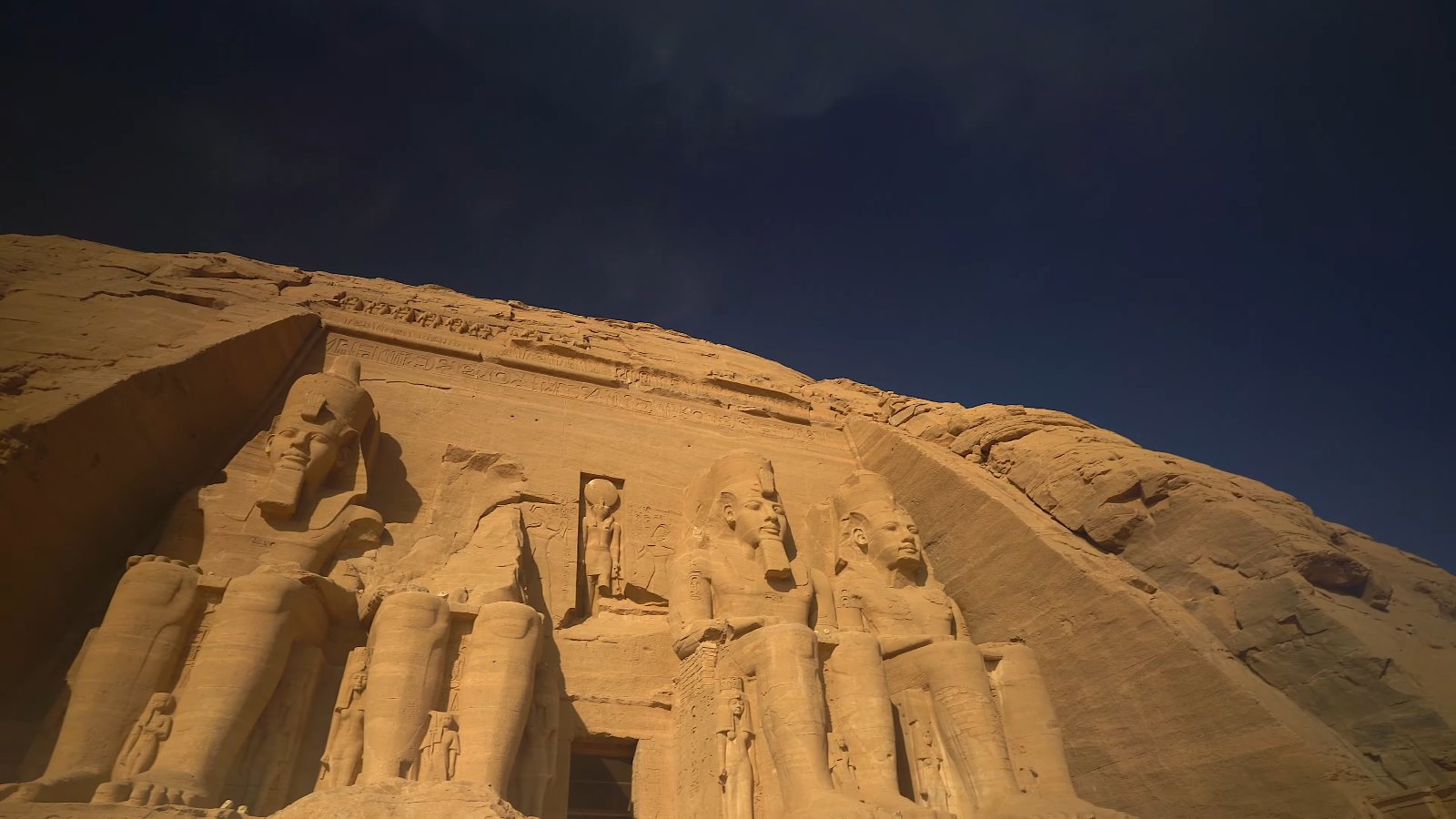 The seated giants of Abu Simbel's Great Temple, cut into the rock under a deep blue sky