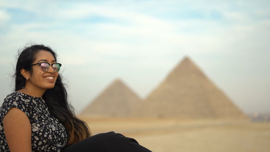 Meenu smiling on the Giza plateau, with two pyramids behind her