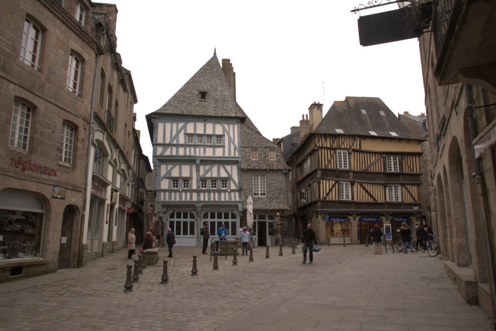 A cobbled square in Dinan framed by half-timbered houses, one of them white under a steep slate roof