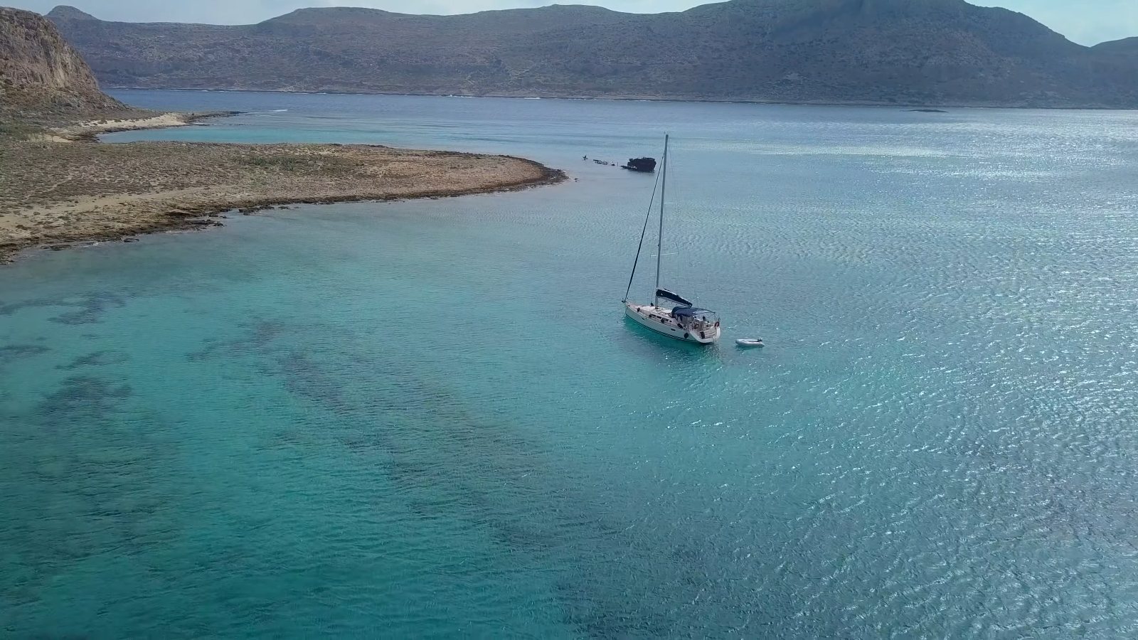 Drone view of our sailing yacht at anchor in a clear turquoise lagoon