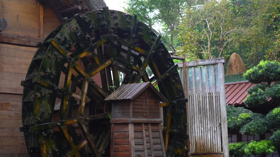 A wooden water wheel beside a small hut in Nan Lian Garden