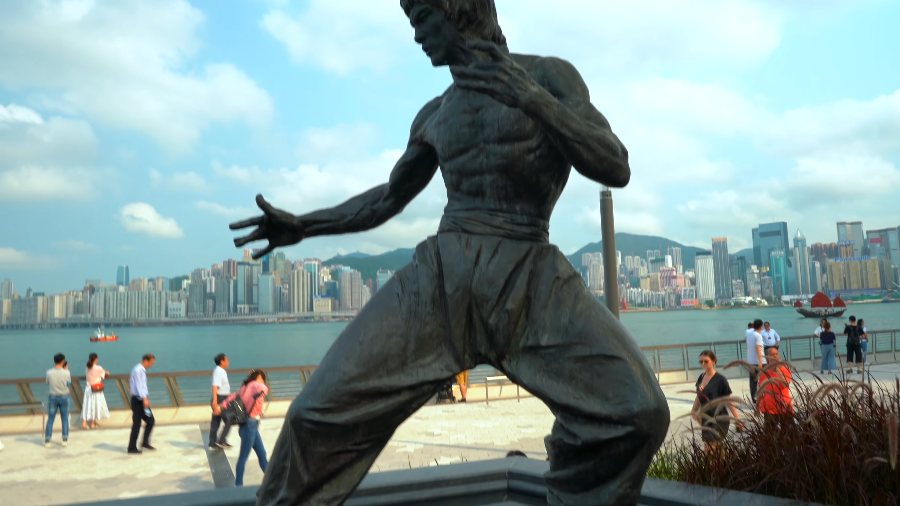 Bruce Lee's statue in its fighting pose on the Avenue of Stars, with the harbour behind