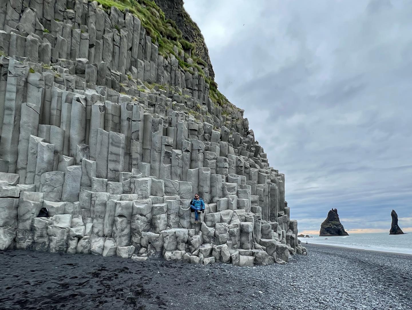 Meenu on the basalt columns at Reynisfjara, above the black pebbles, with the Reynisdrangar sea stacks offshore