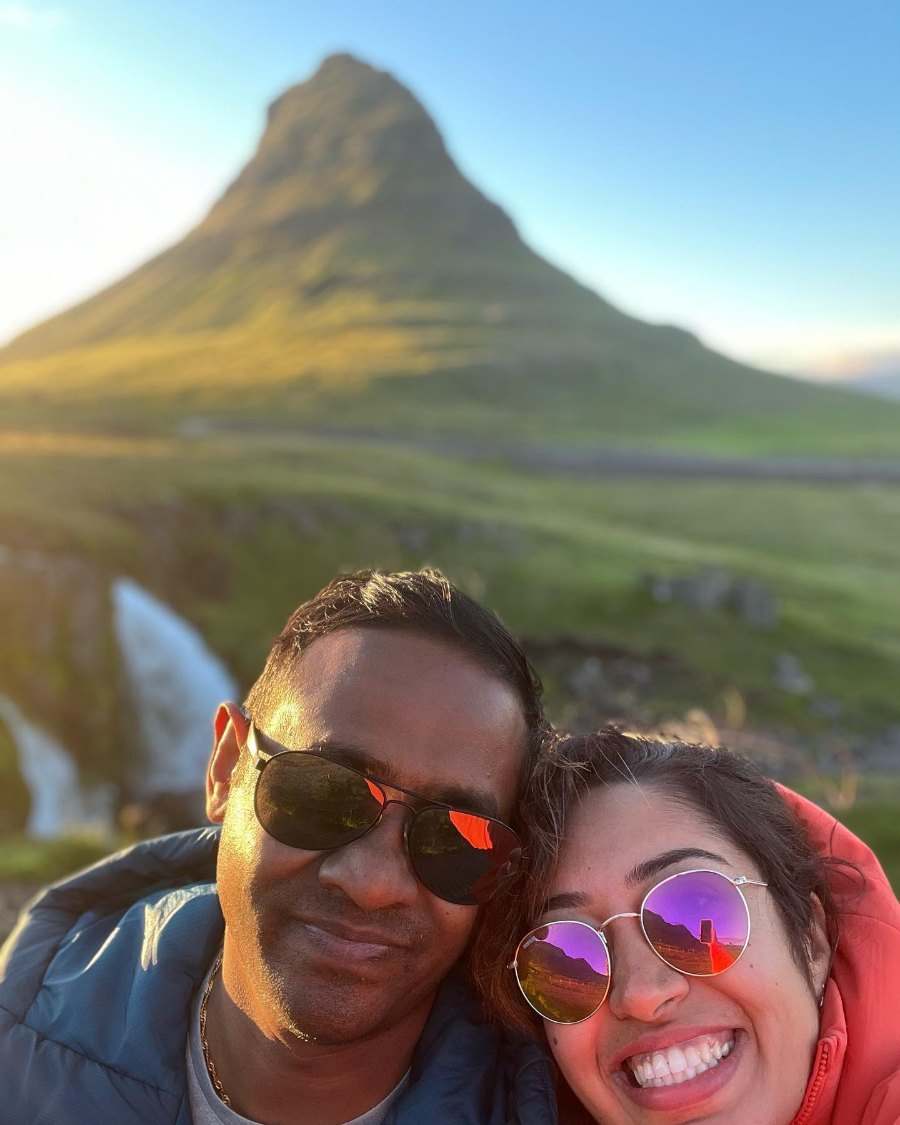 Meenu and Praddy's selfie in front of Kirkjufell, with Kirkjufellsfoss behind them in low, warm sun