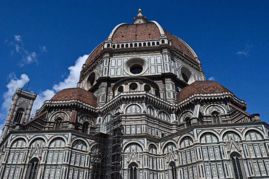 The Duomo's red-tiled dome and marble-banded walls against a blue sky