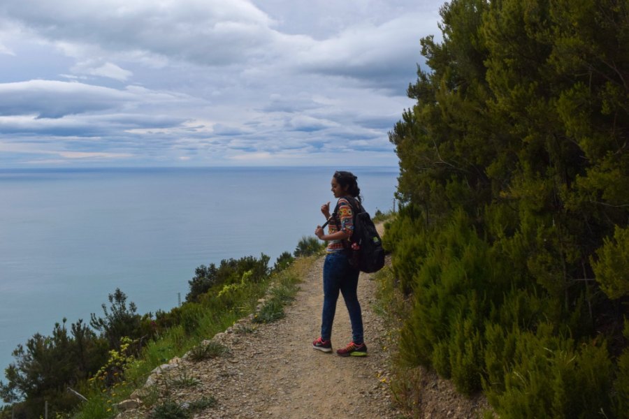 Meenu on a narrow dirt path along the cliff edge, the sea far below