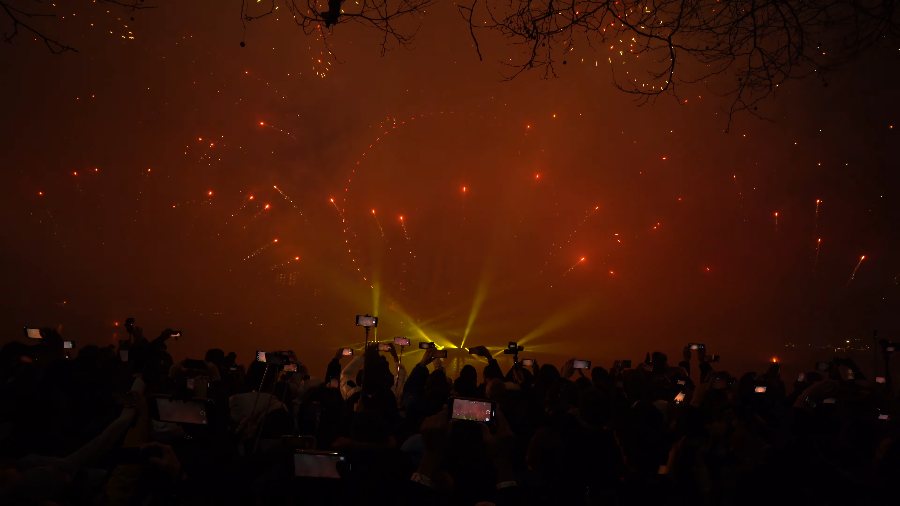 Yellow laser beams fanning up through orange smoke over the crowd
