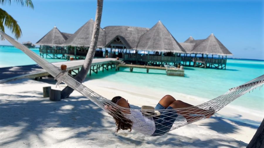 Meenu in a hammock under the palms, facing the overwater restaurant