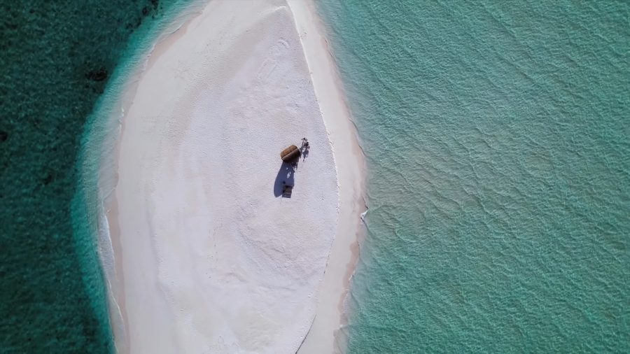 Drone view of a narrow white sandbank in deep green water