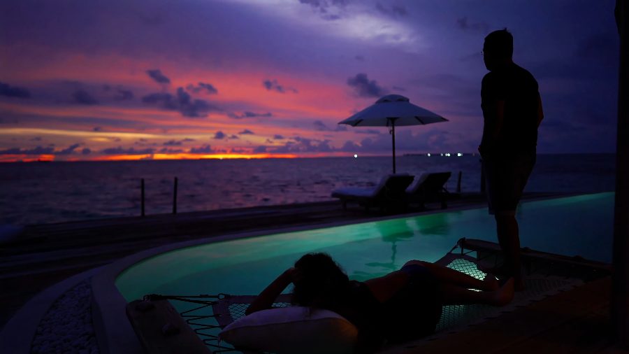 Purple and orange sunset over the villa pool, with our silhouettes on the deck