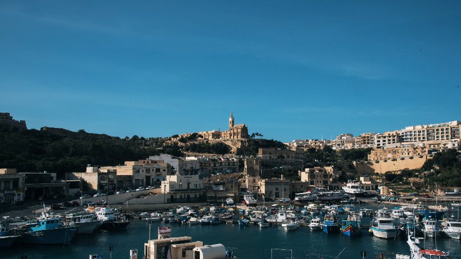 Mġarr harbour full of boats, with the chapel on the hill above