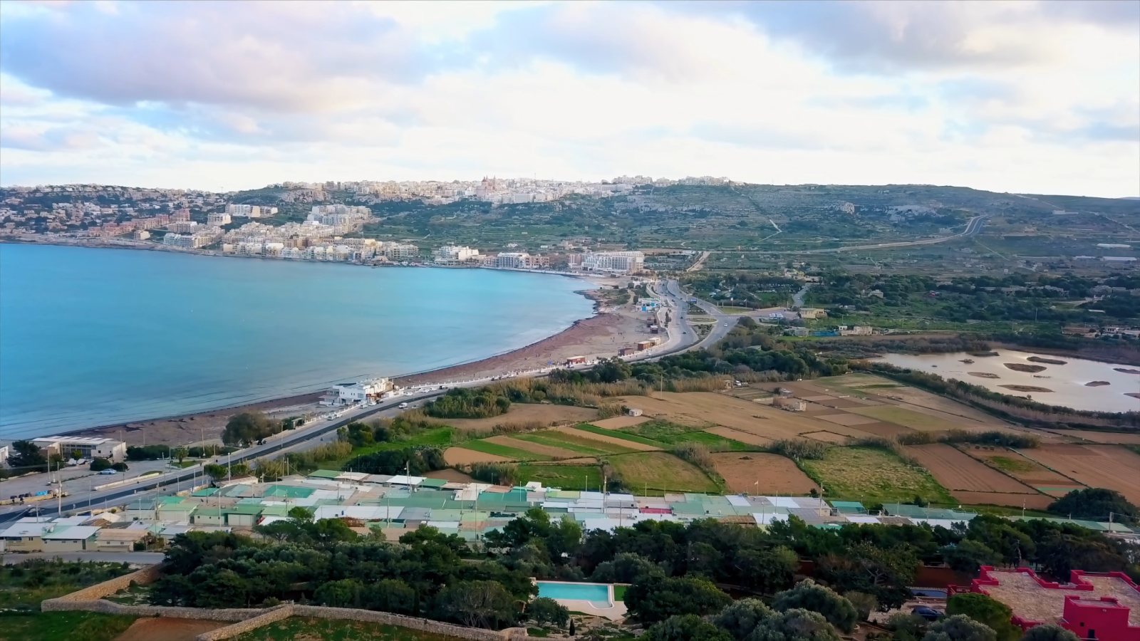 Mellieħa Bay from the drone, with the long sandy beach, the fields behind it and the town on the ridge