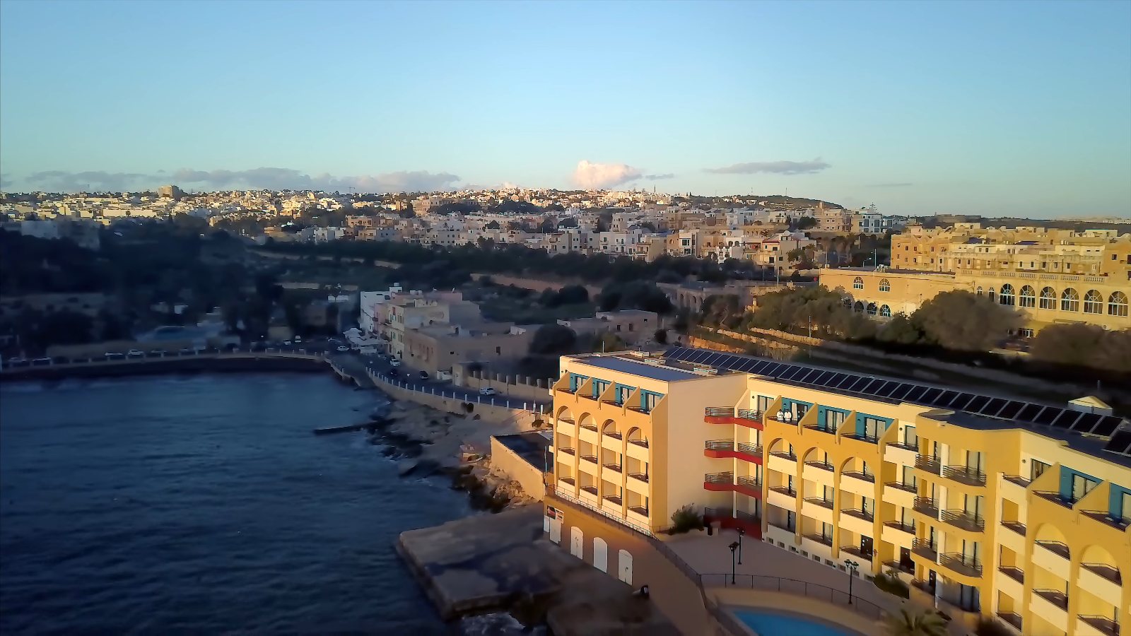 Our yellow hotel at the water's edge on St George's Bay, with the town on the hill behind, from the drone