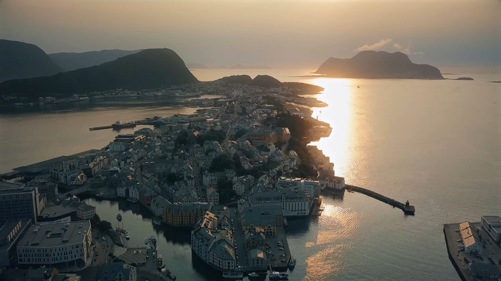 Drone view of Ålesund at sunset, the old town packed onto its islands and the sun on the sea