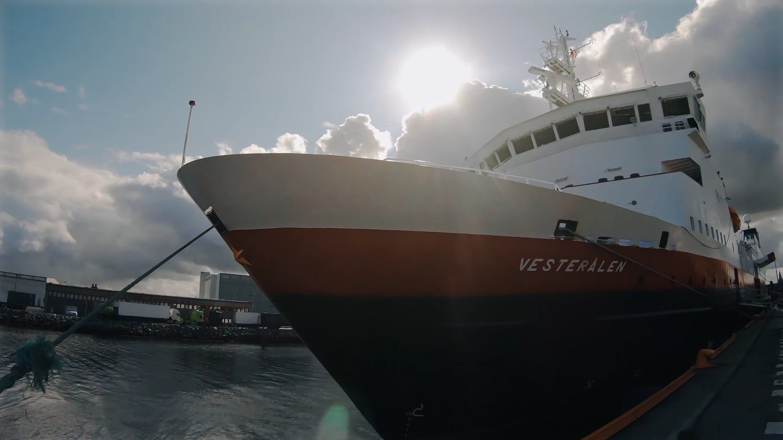 MS Vesterålen at the quay, its name on the bow and the sun behind the ship