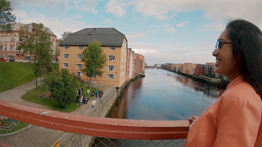 Meenu on Trondheim's Old Town Bridge, with painted wharf houses along the river