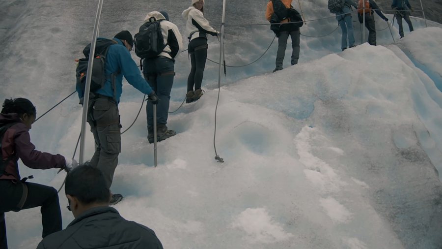 A roped line of walkers in crampons on the glacier ice
