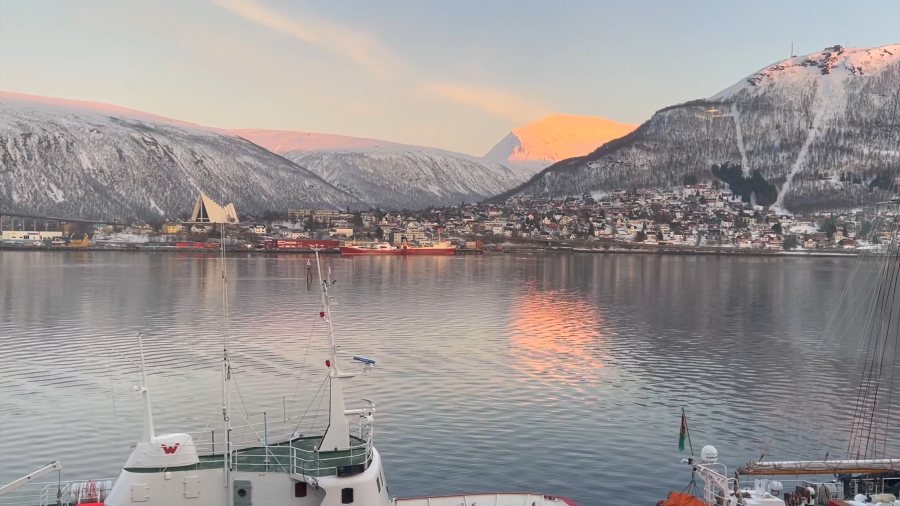Tromsø's harbour at sunset, with pink light on the mountains and the Arctic Cathedral across the water