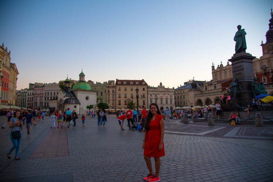 Meenu in a red dress on Kraków's Main Square, below the statue of Adam Mickiewicz