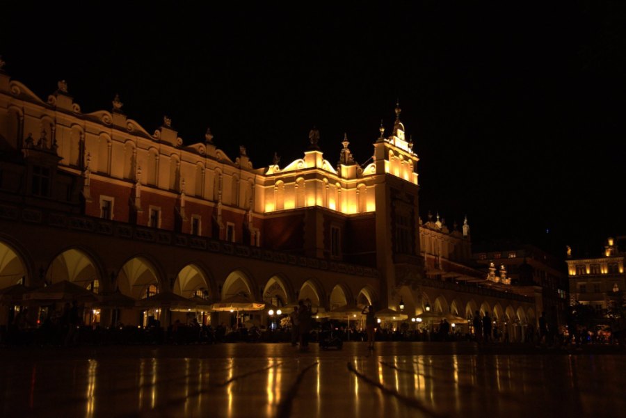 The arcades of the Cloth Hall glowing gold on the Main Square at night