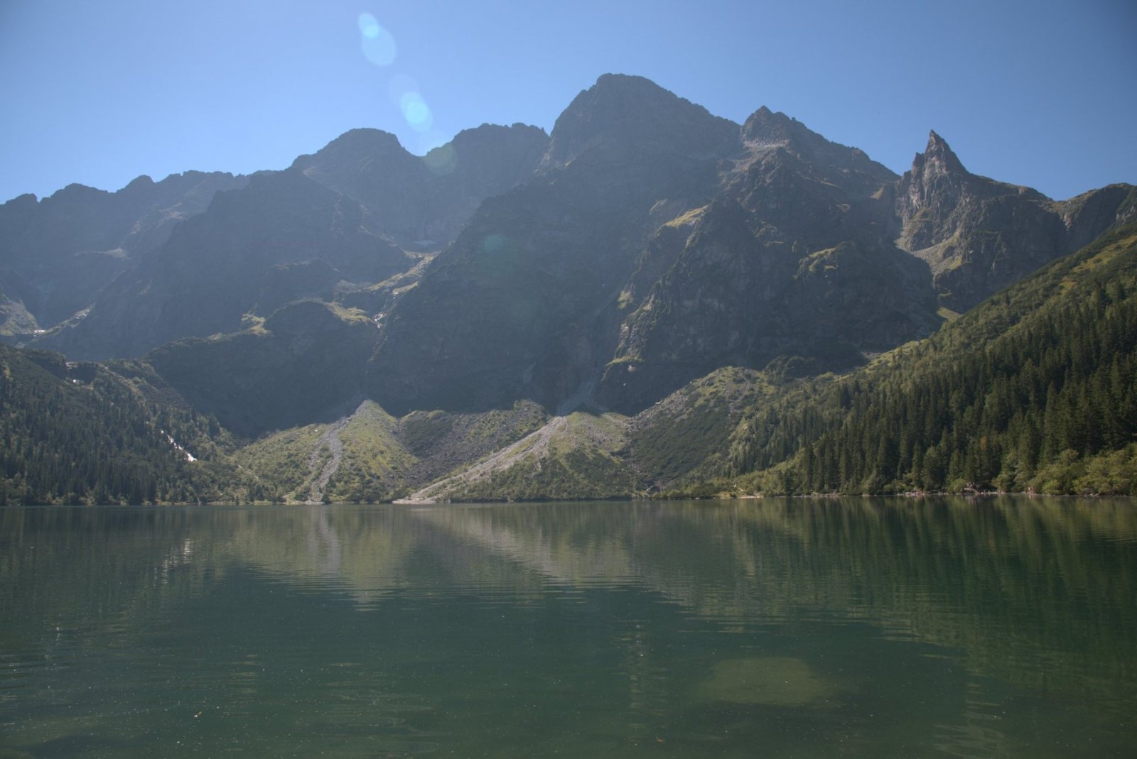 Morskie Oko in a ring of grey Tatra peaks, the still water reflecting the slopes