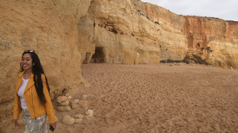 Meenu laughing on an empty beach below the golden cliffs
