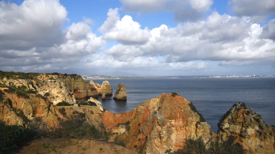 The cliffs and sea stacks of Ponta da Piedade from the clifftop, under big white clouds