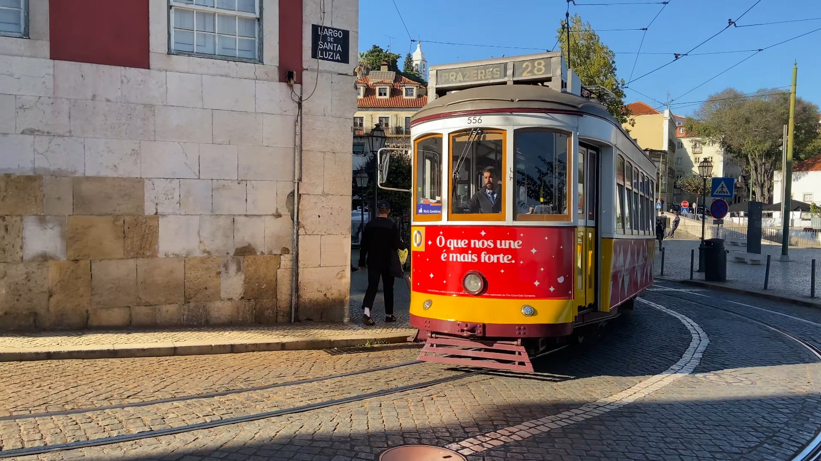 A yellow and red number 28 tram coming round the corner at Largo de Santa Luzia