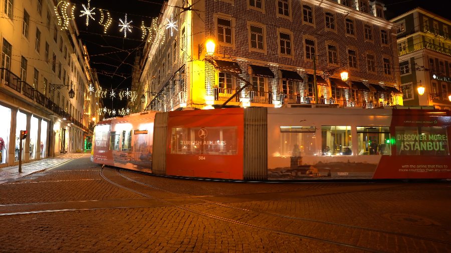 A tram passing under Christmas lights at night