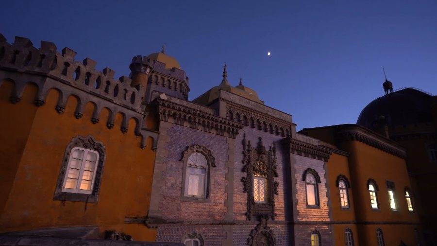 Pena Palace's ochre walls and turrets under a deep blue sky at dusk