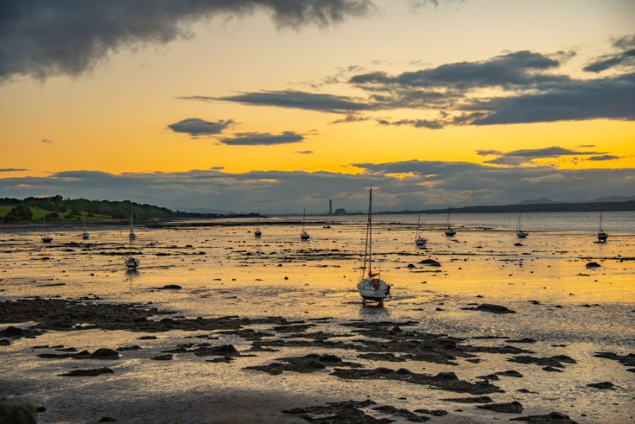 Sunset over the Firth of Forth, with small boats resting on the mud at low tide