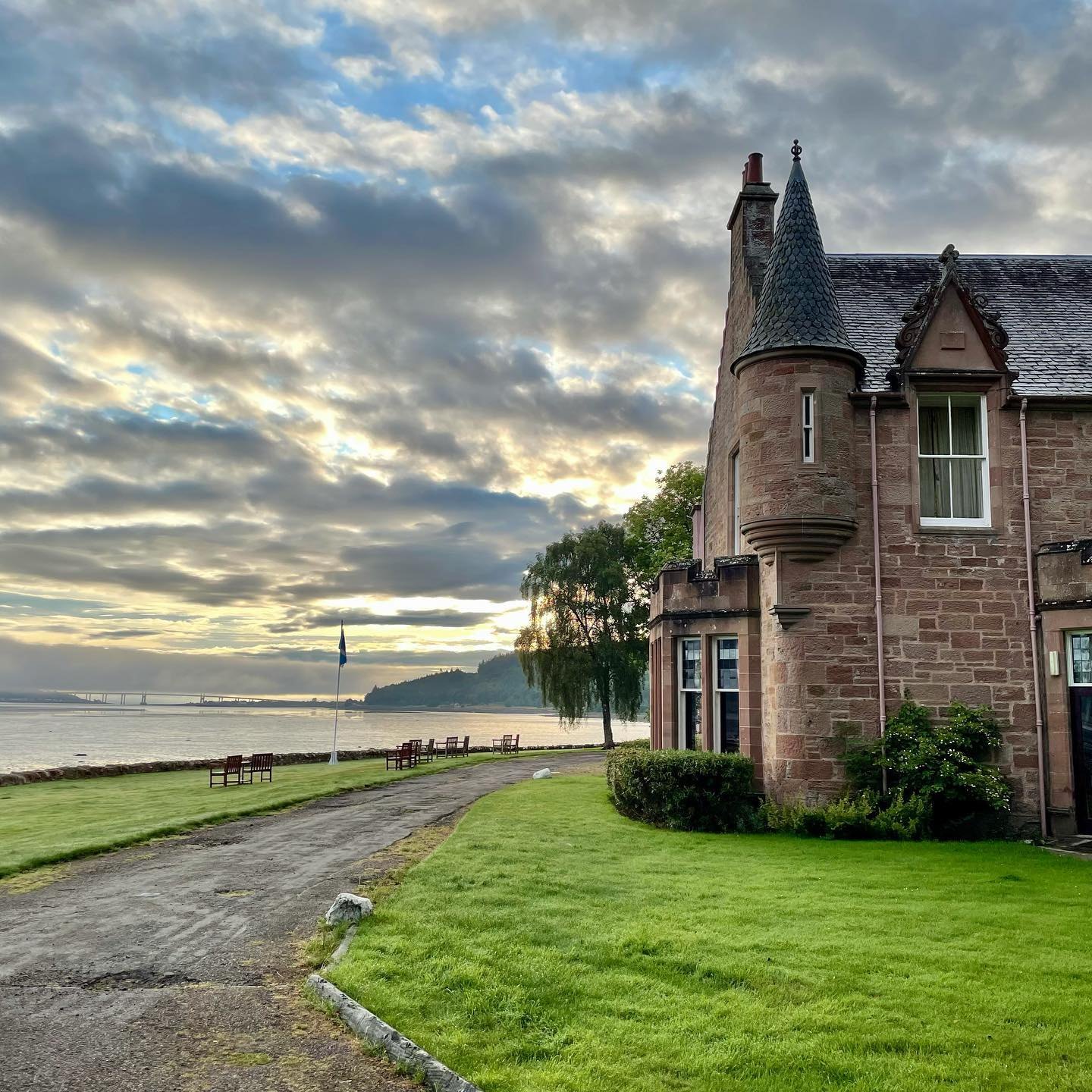 Bunchrew House, a turreted pink-stone mansion on the shore of the Beauly Firth, under a wide cloudy sky